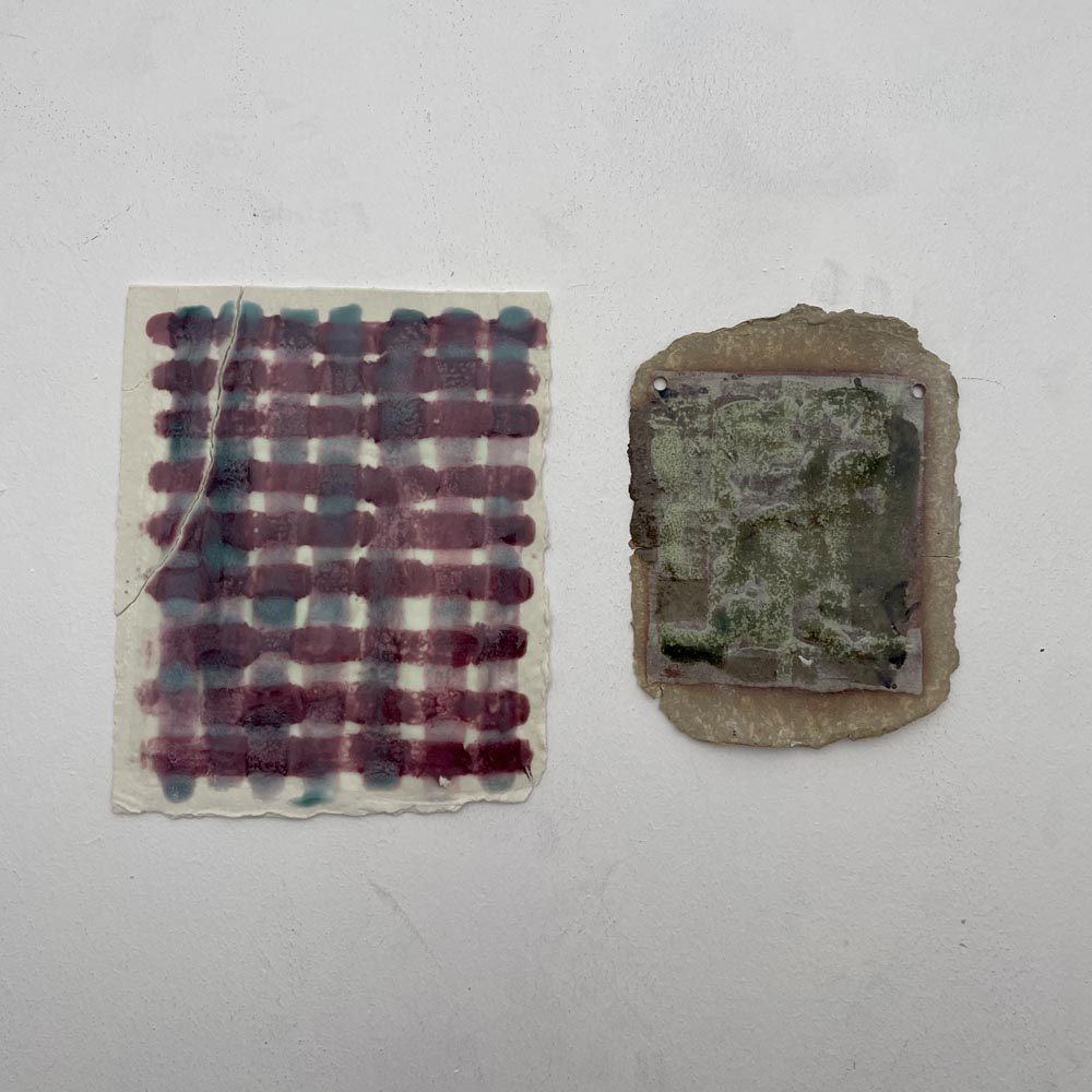 two flat ceramic pieces, the left one is porcelain glazed in a pink and blue lattice and the right one is buff glazed in greens.
