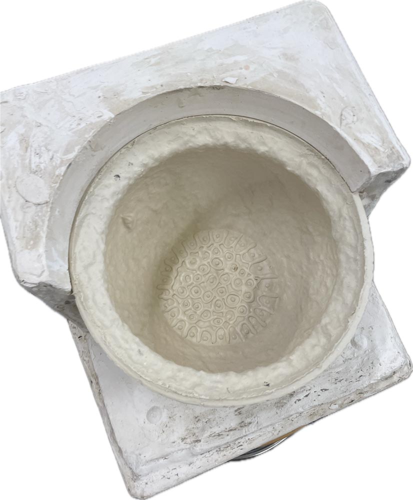 A slip cast chamber pot half out of its plaster mould.
