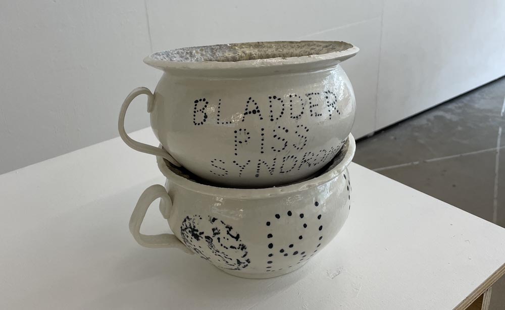 Two porcelain chamber pots stacked on a white surface.